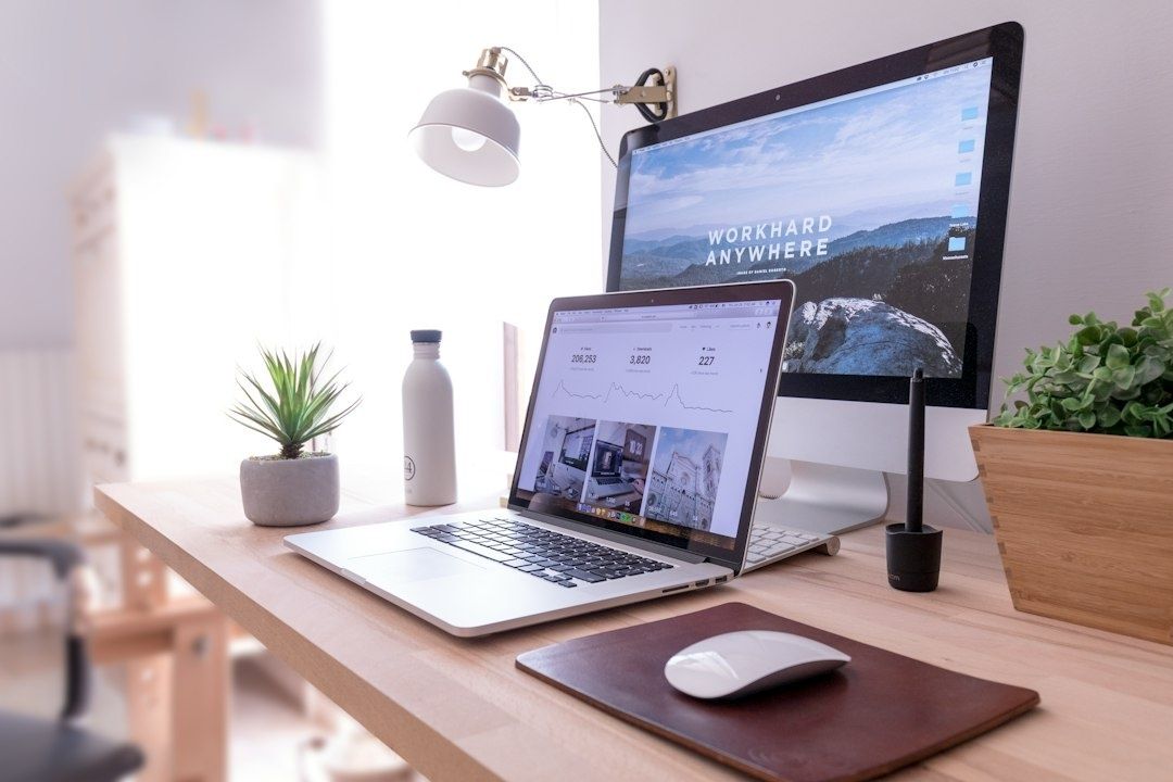 Hembetsplats med laptop, bildskärm och tillbehör på skrivbord