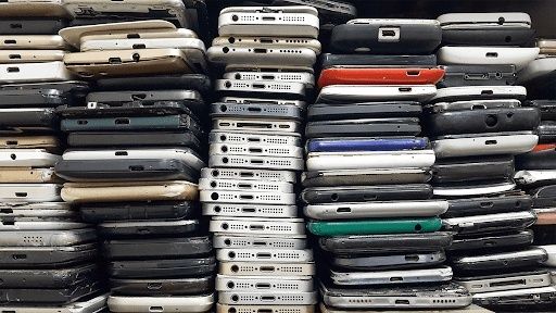 Staplar av begagnade mobiltelefoner i olika färger och modeller